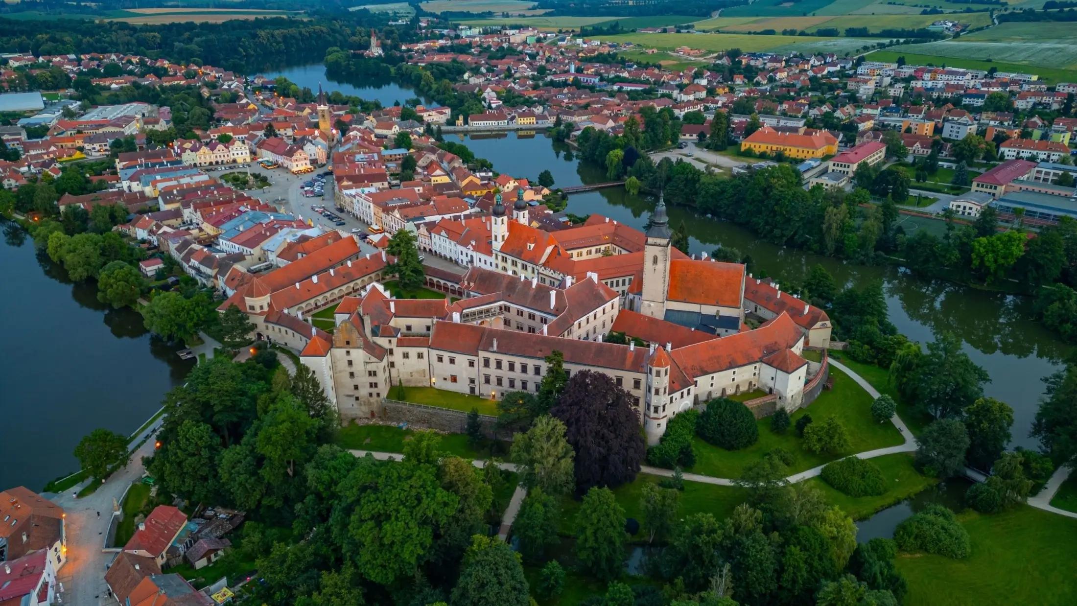 Panoramatický záběr na město Telč. Konkrétně na jeho zámek, část náměstí a okolní řeky.