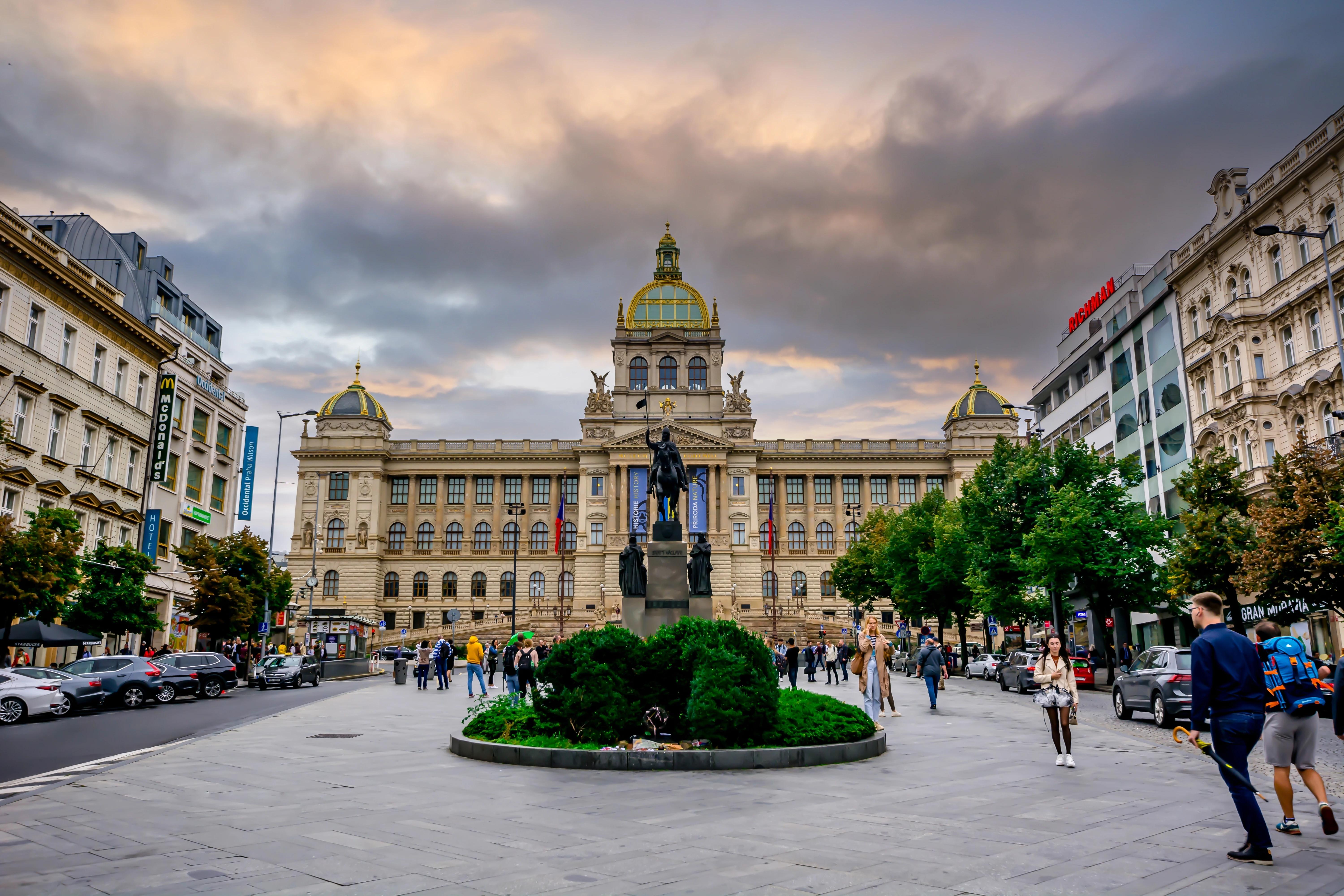 Pohled na horní část Václavského náměstí, kde je Národní muzeum. Lidé jsou okolo sochy koně. 