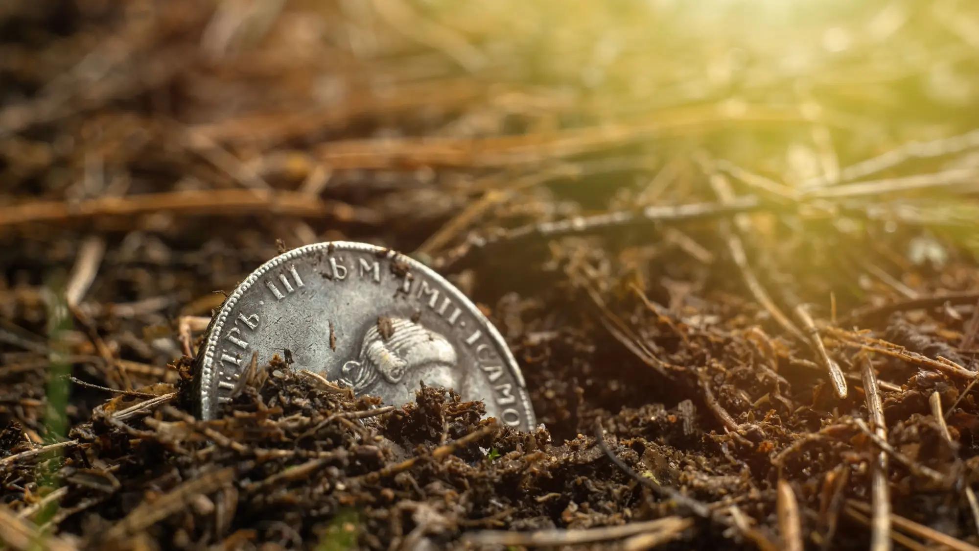 Stará mince napůl zarytá v zemi
