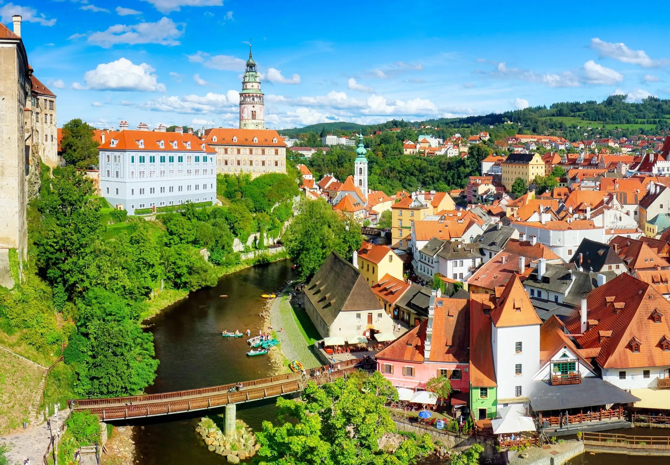 Letecký záběr na Český Krumlov. Vidět jde nalevo zámek, vedle něj řeka s mostem a na pravé straně město.