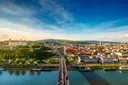Letecký pohled na Bratislavu. Vepředu jde vidět řeka Dunaj, přes kterou vede most. Na levé straně je v dáli Bratislavský zámek a na pravé ostatní domy města.