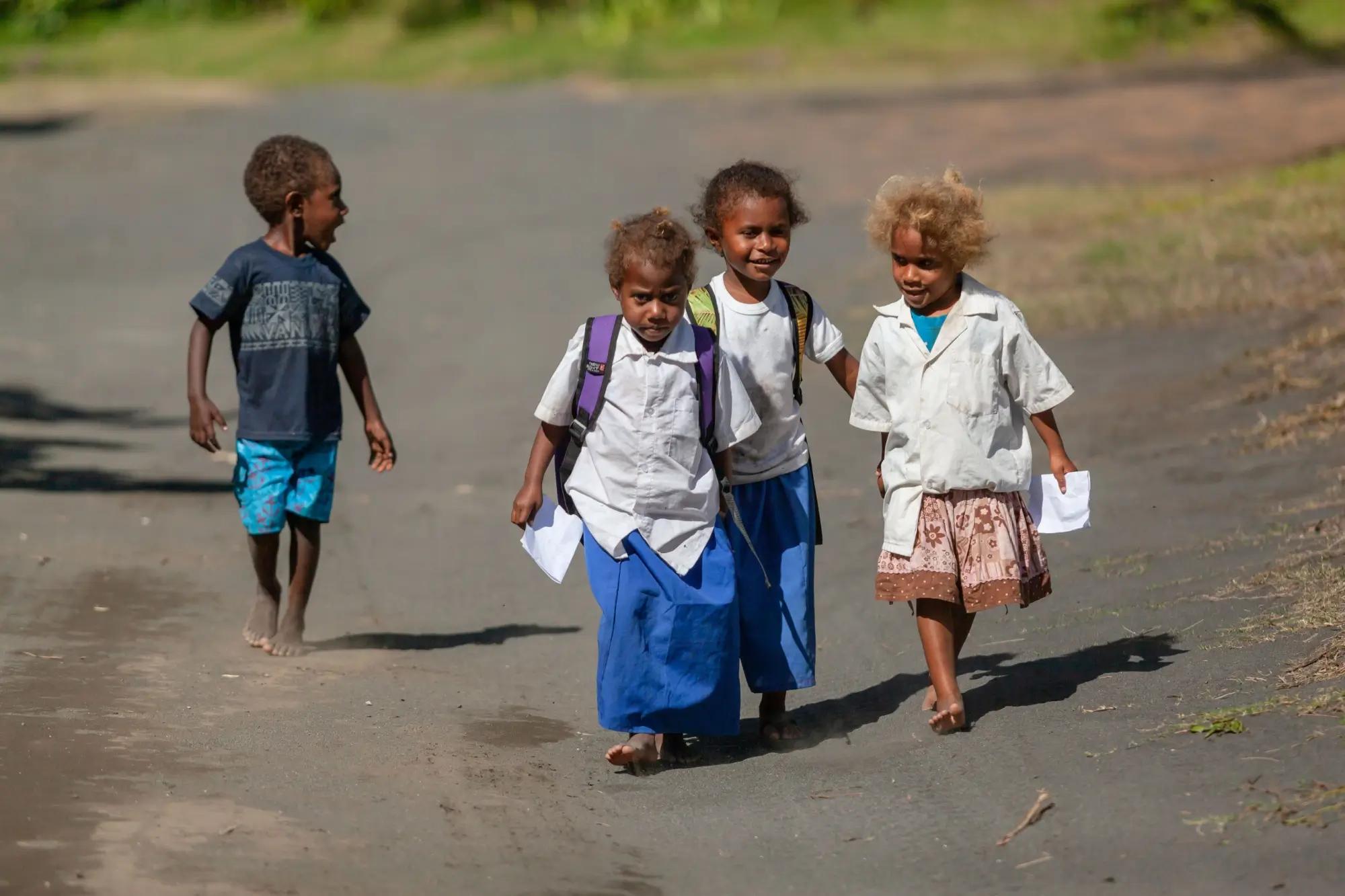 Skupina čtyř dětí z Melanésie, z nichž jedno je blond
