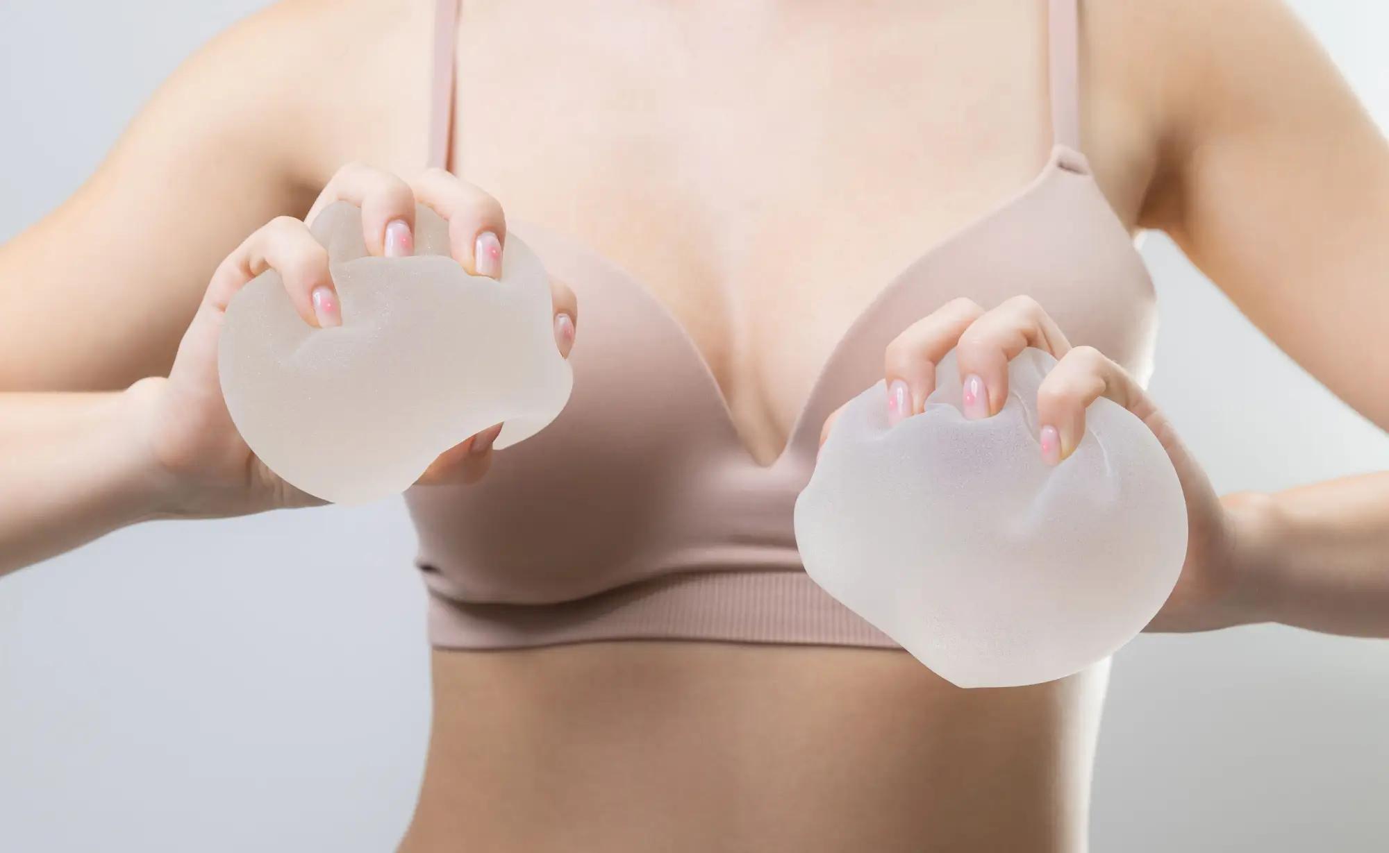 žena drží v rukou dva silikonové prsní implantáty