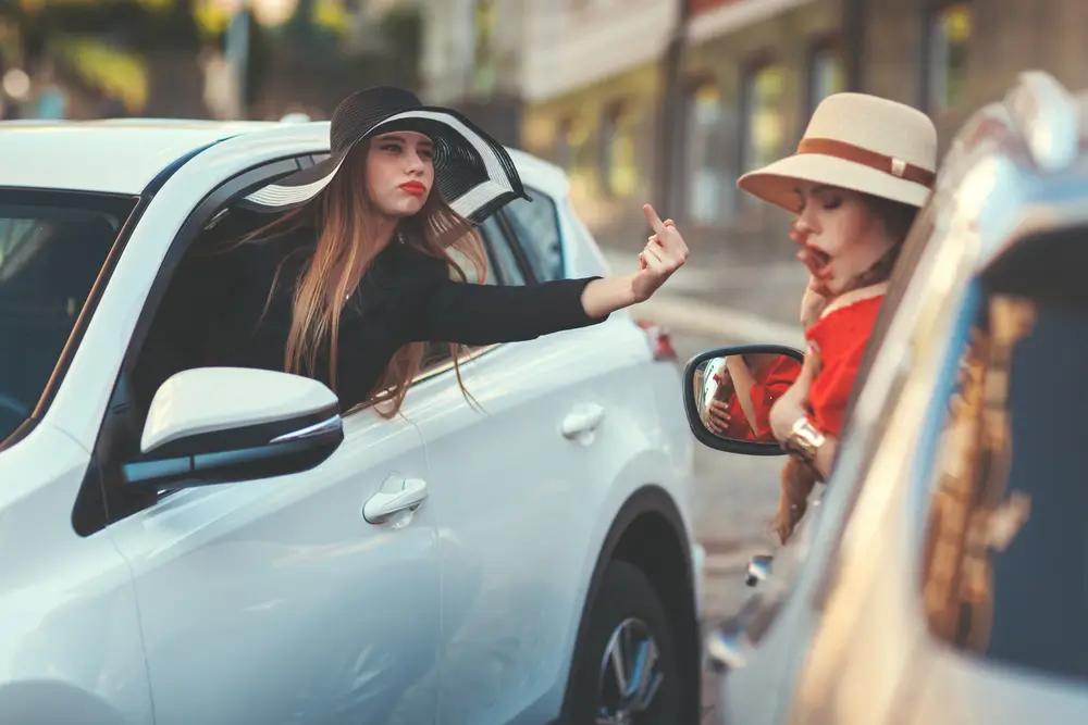 Žena z okna auta ukazuje hrubé gesto jinému řidiči