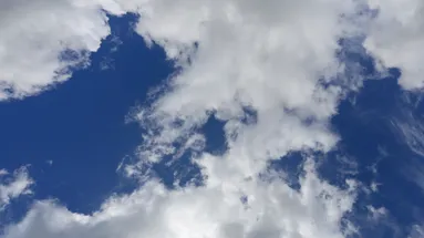 Pohled na poměrně jasnou oblohu s mraky, za kterými se schovává slunce.