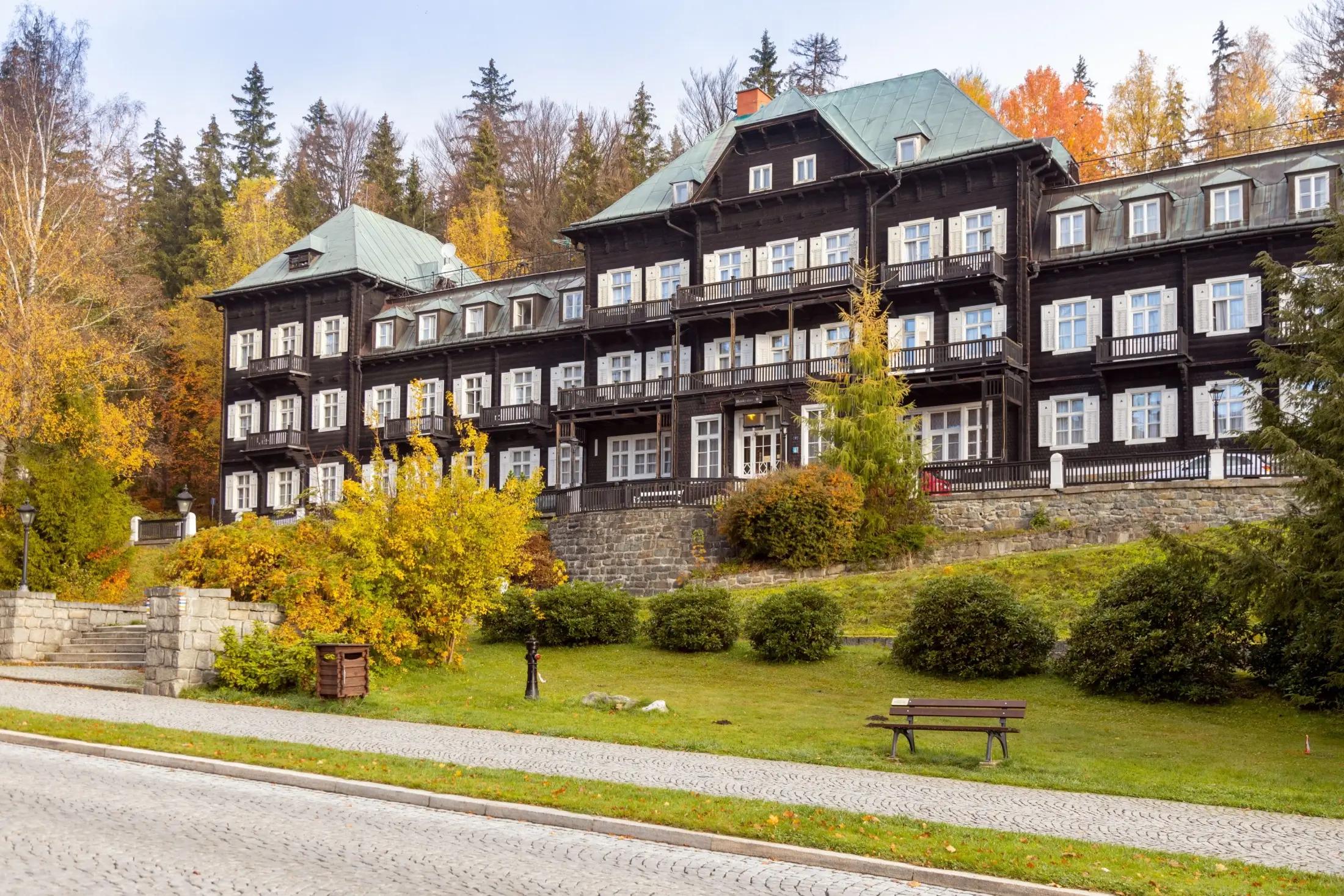 Slezský dům v Karlově Studánce. Je podzim, jelikož okolní domy mají žluté až oranžové listí.