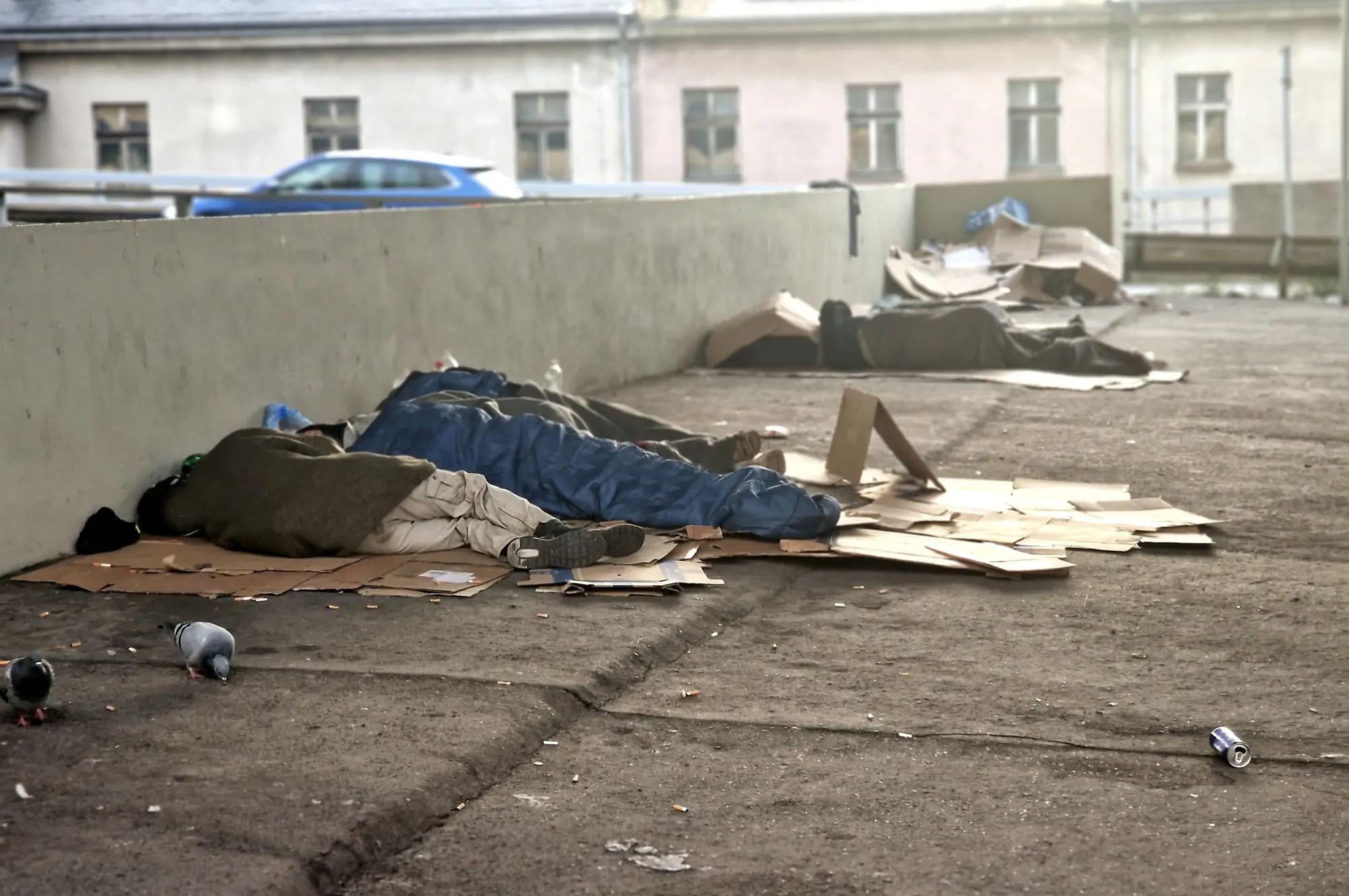 lidé bez domova spí na kartonech na ulici