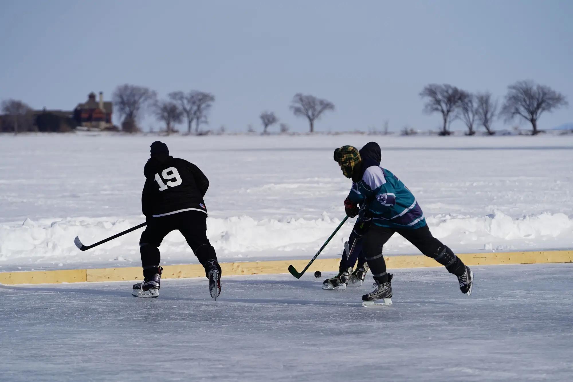 Muži hrají hokej na zamrzlém rybníku