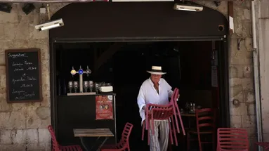 italský muž vynáší v restauraci židle na zahrádku
