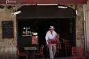 italský muž vynáší v restauraci židle na zahrádku