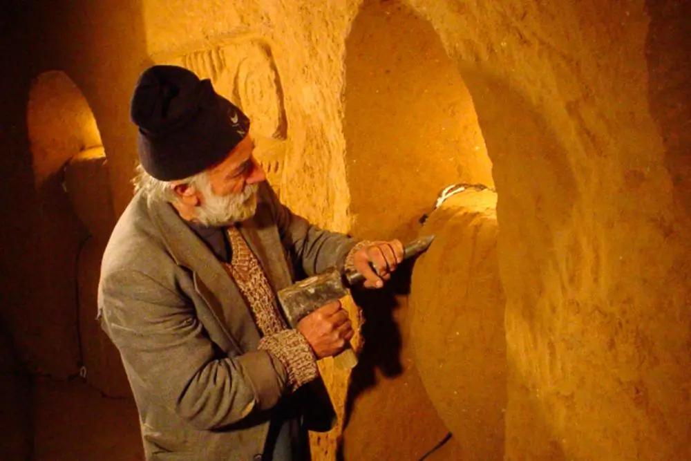 Muž vysekává do zdi ornament