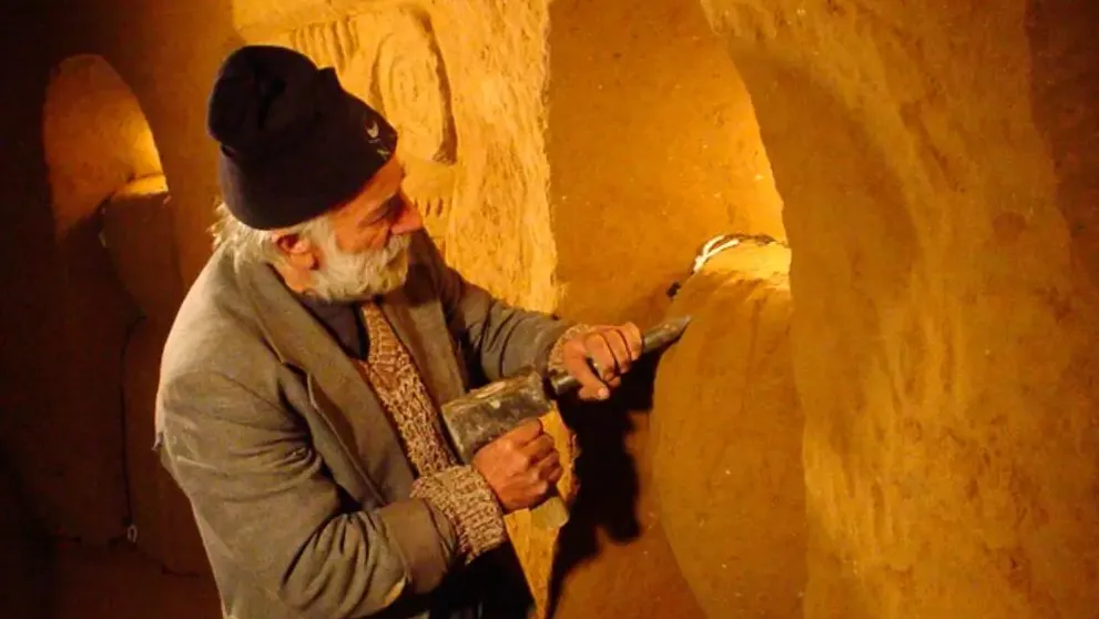 Muž vysekává do zdi ornament