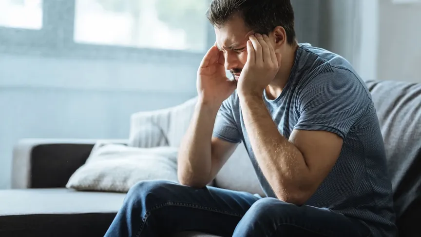 Sklíčený muž sedí na gauči