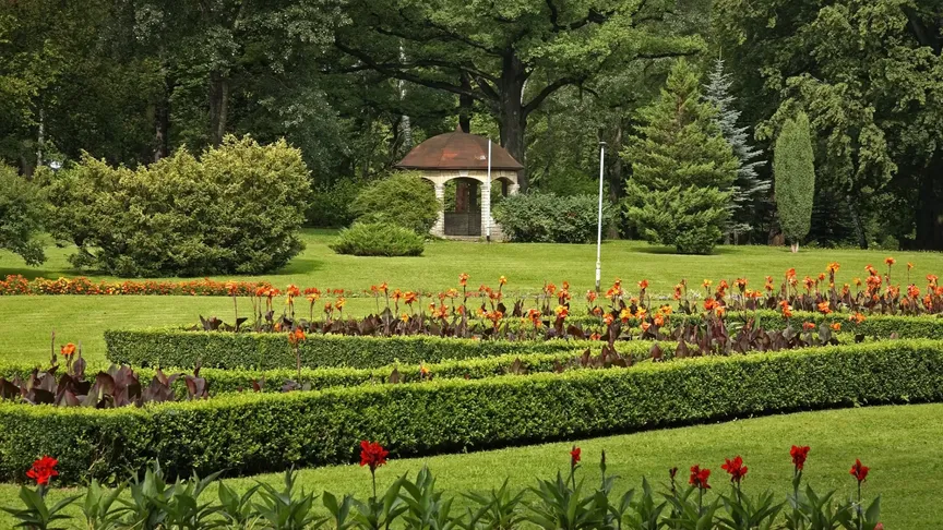 Krásný zelený park s květinami a malými živými ploty v obležení lesů v Kudowa-Zdroj. Polsko