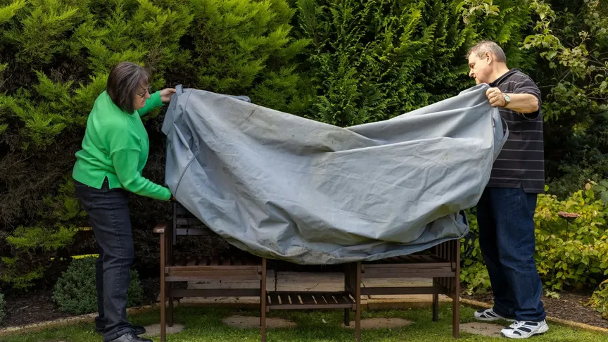 Starší pár zakrývá zahradní nábytek