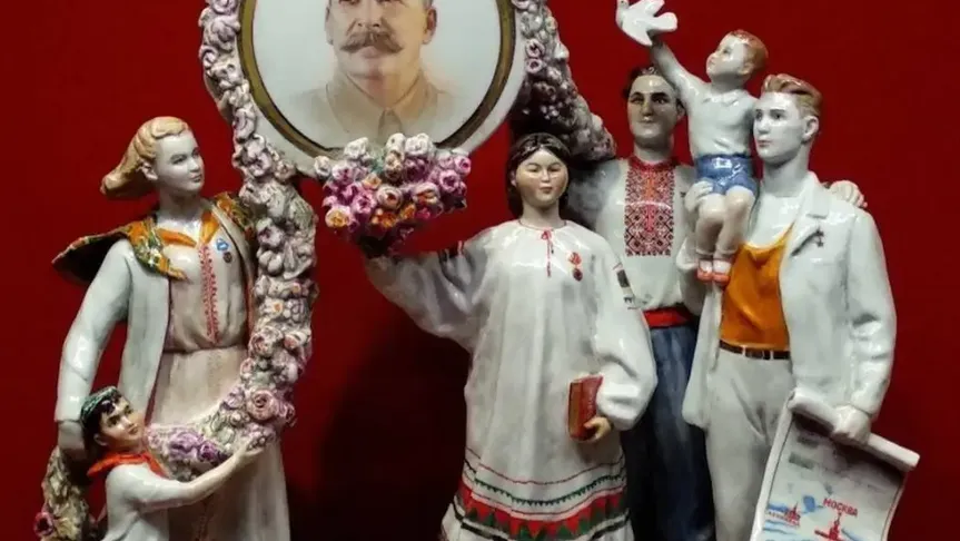 Porcelánové figurky v ruských krojích nesou portrét Stalina
