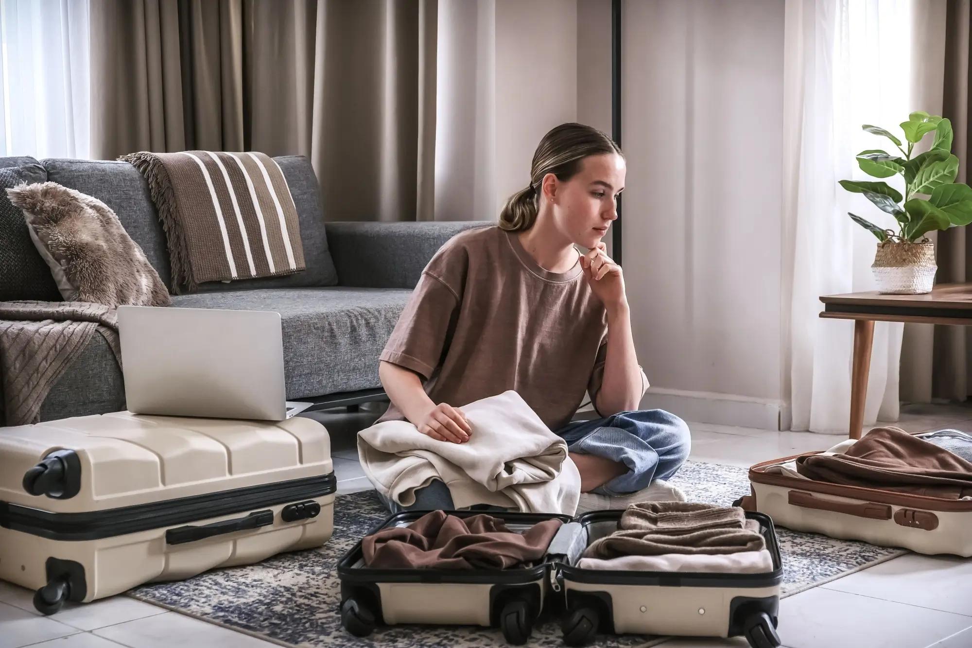 Žena přemýšlí nad kufry, jak se sbalit na dovolenou
