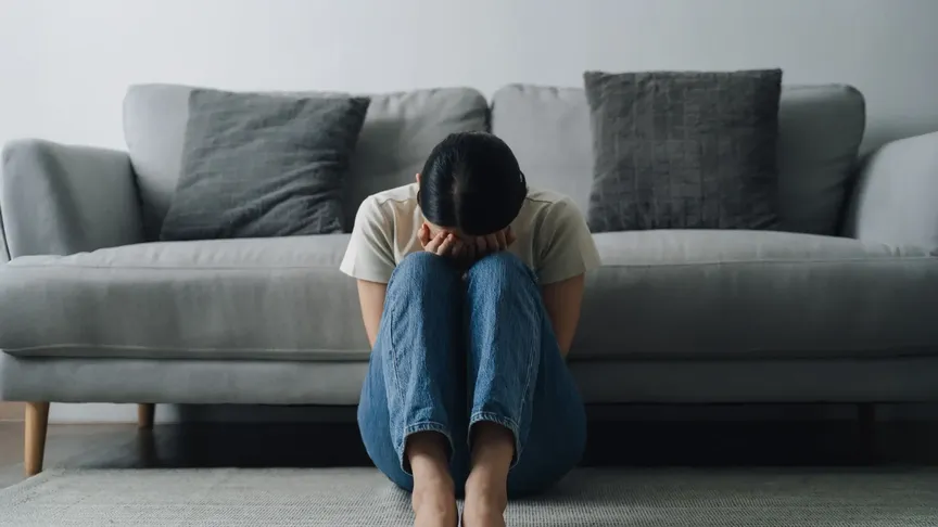 Žena schoulená na zemi brečí