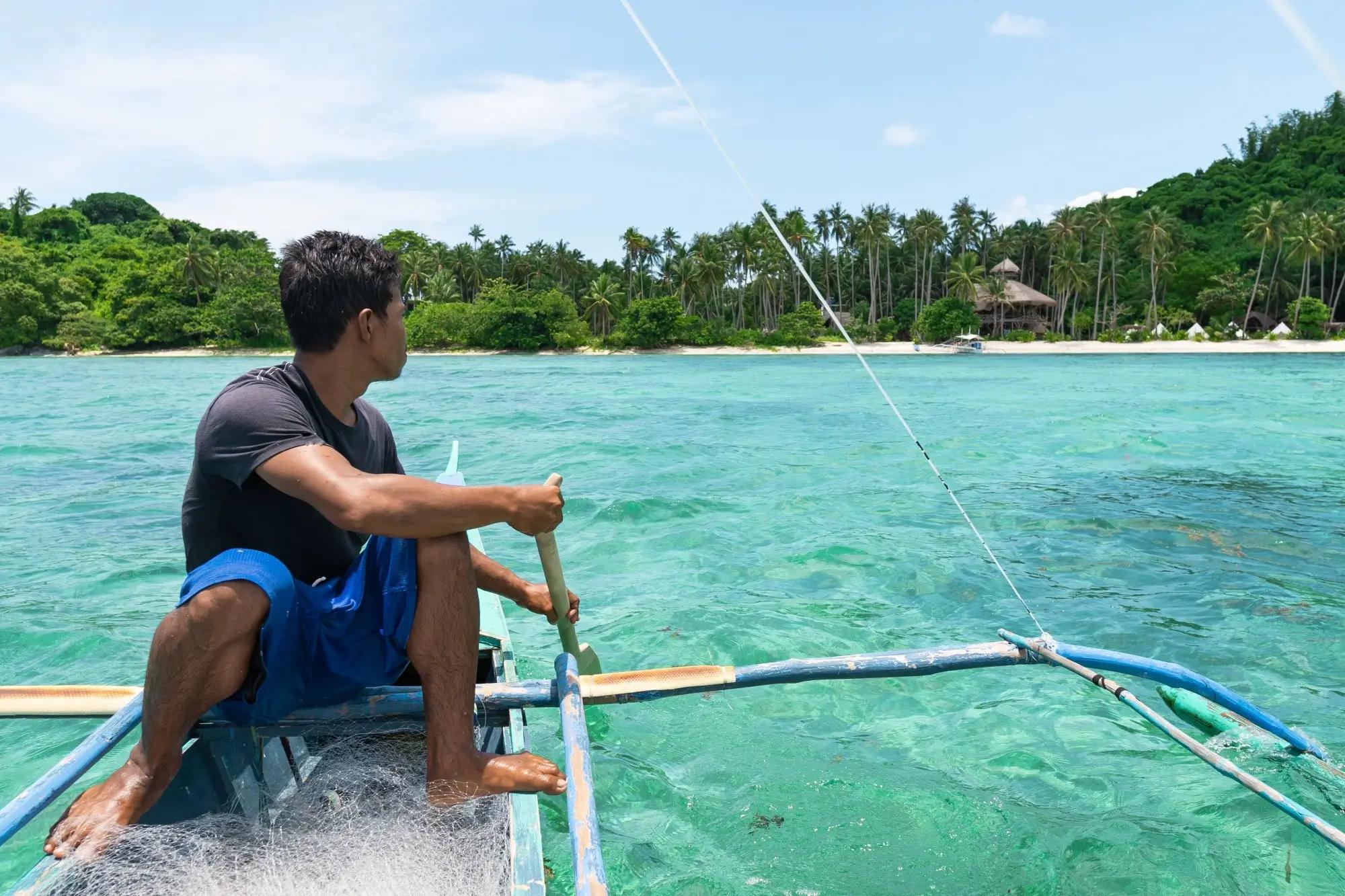 Filipínský rybář na své loďce