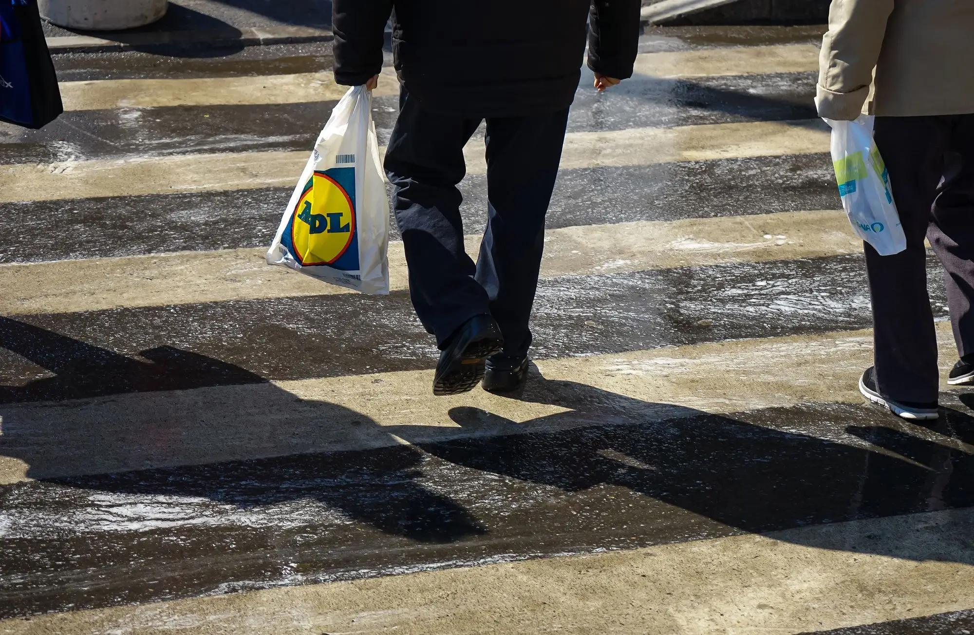 muž na ulici s igelitkou Lidl