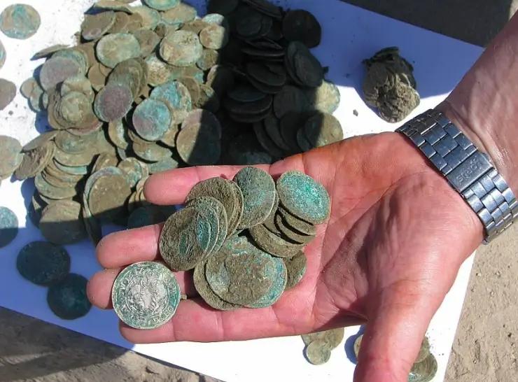 muž drží v ruce staré mince