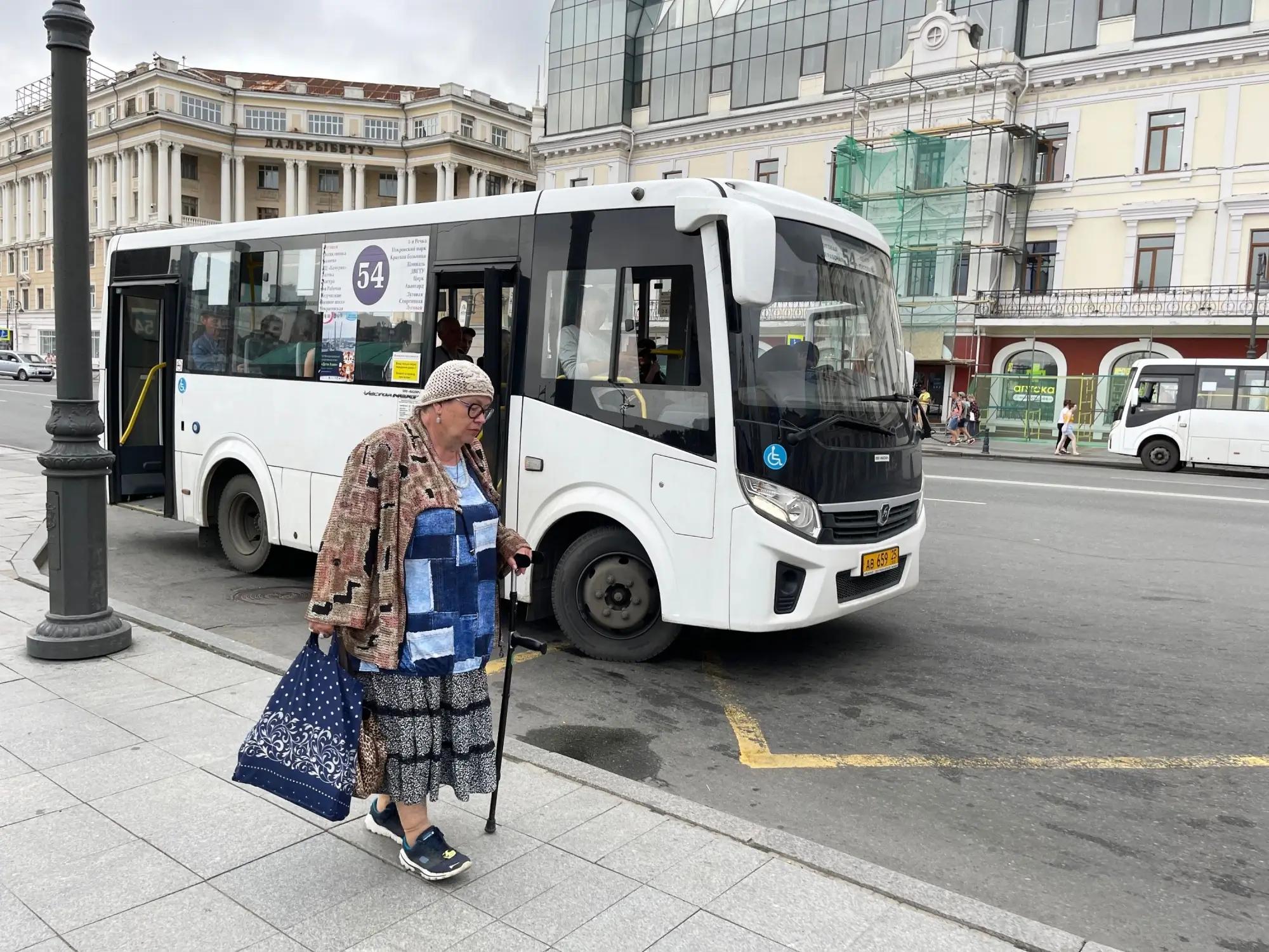 Starší paní s berlí jde do autobusu.
