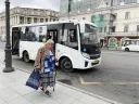 Starší paní s berlí jde do autobusu.