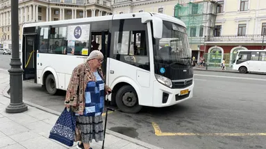 Starší paní s berlí jde do autobusu.