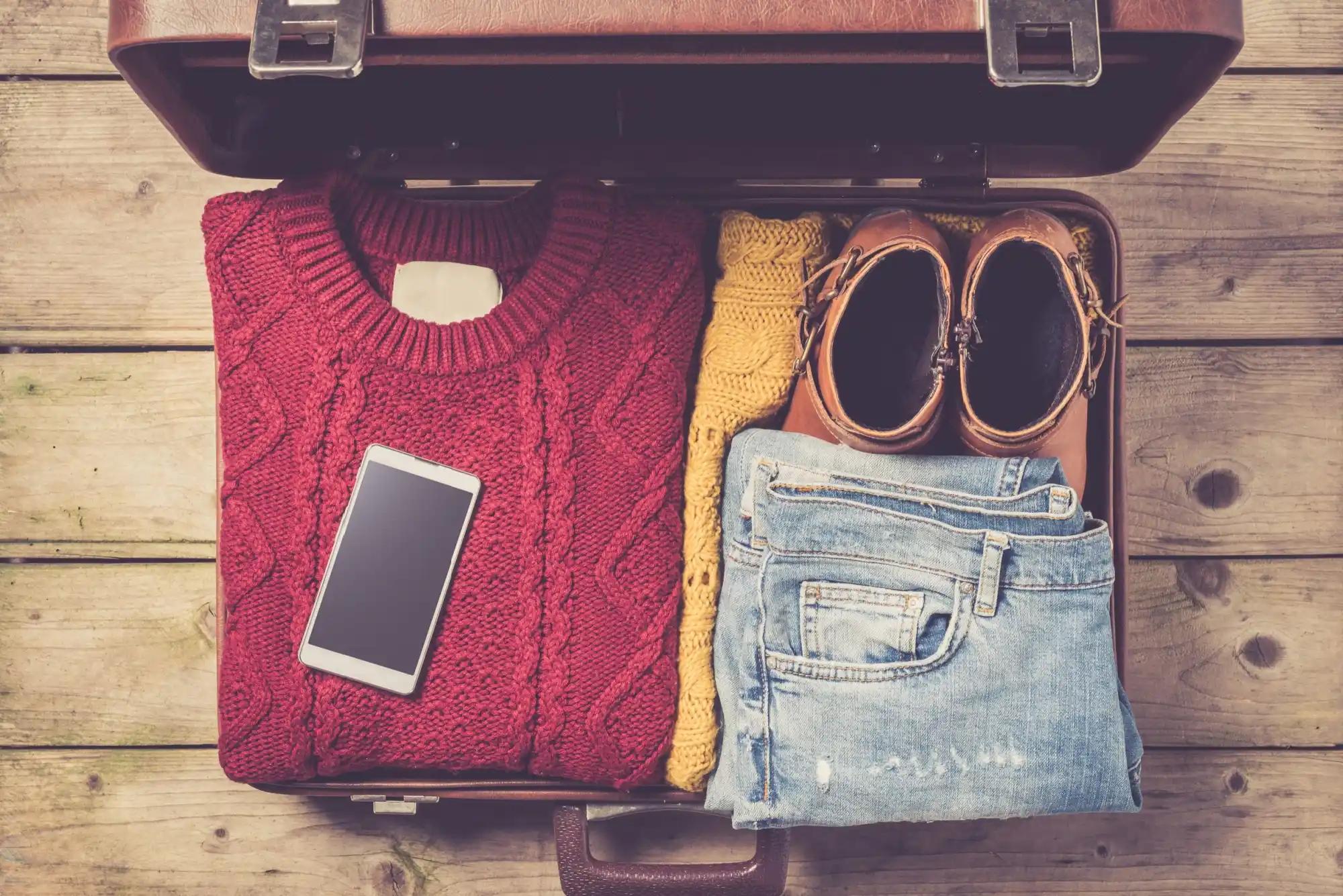 otevřený kufr plný oblečení na podzimní dovolenou