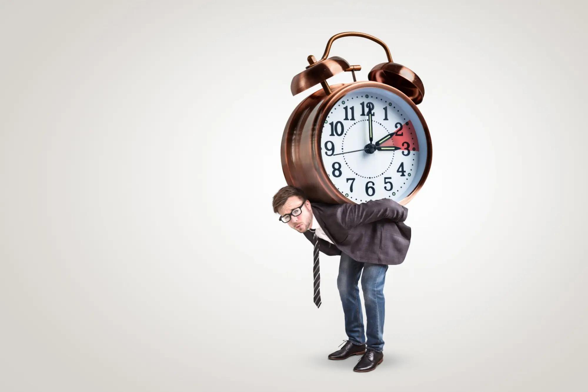 Muž nese na zádech velký budík ukazující jak se mění čas