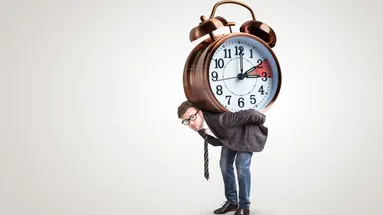 Muž nese na zádech velký budík ukazující jak se mění čas