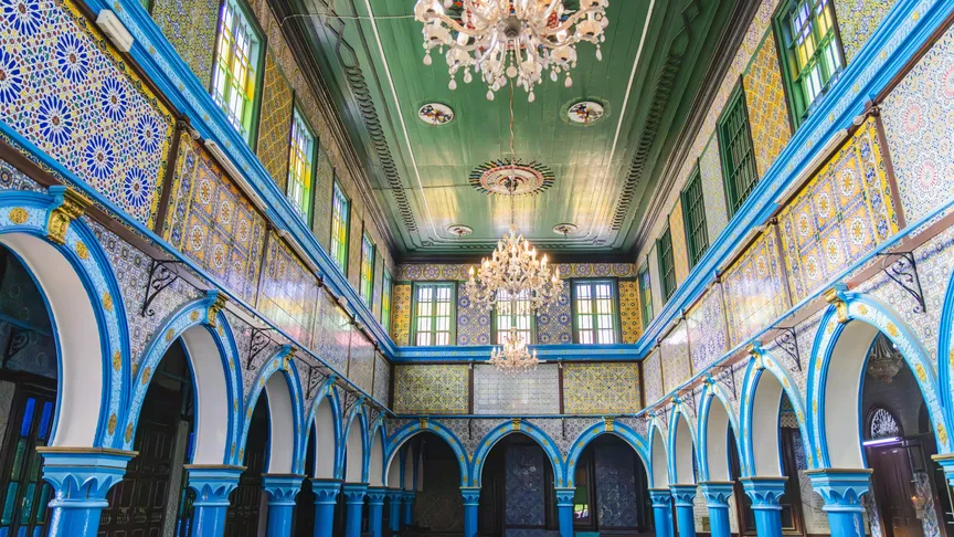 Vnitřní pohled na barevnou synagogu El Ghriba v maurském stylu a s rozsvícenými lustry. Djerba, Medenine, Tunisko. Zdroj: Shutterstock