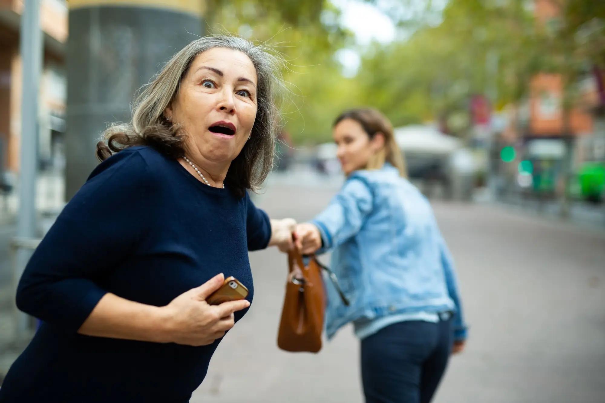 žena je v šoku, právě se jí jiná žena snaží ukrást kabelku