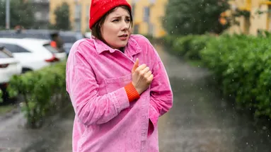 Žena v čepici choulící se do bundy