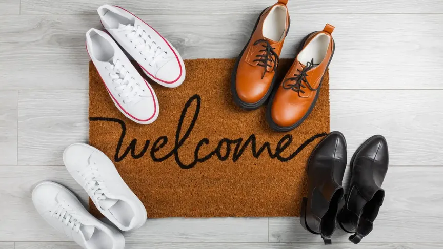 Rohožka s nápisem "welcome" a boty okolo ní