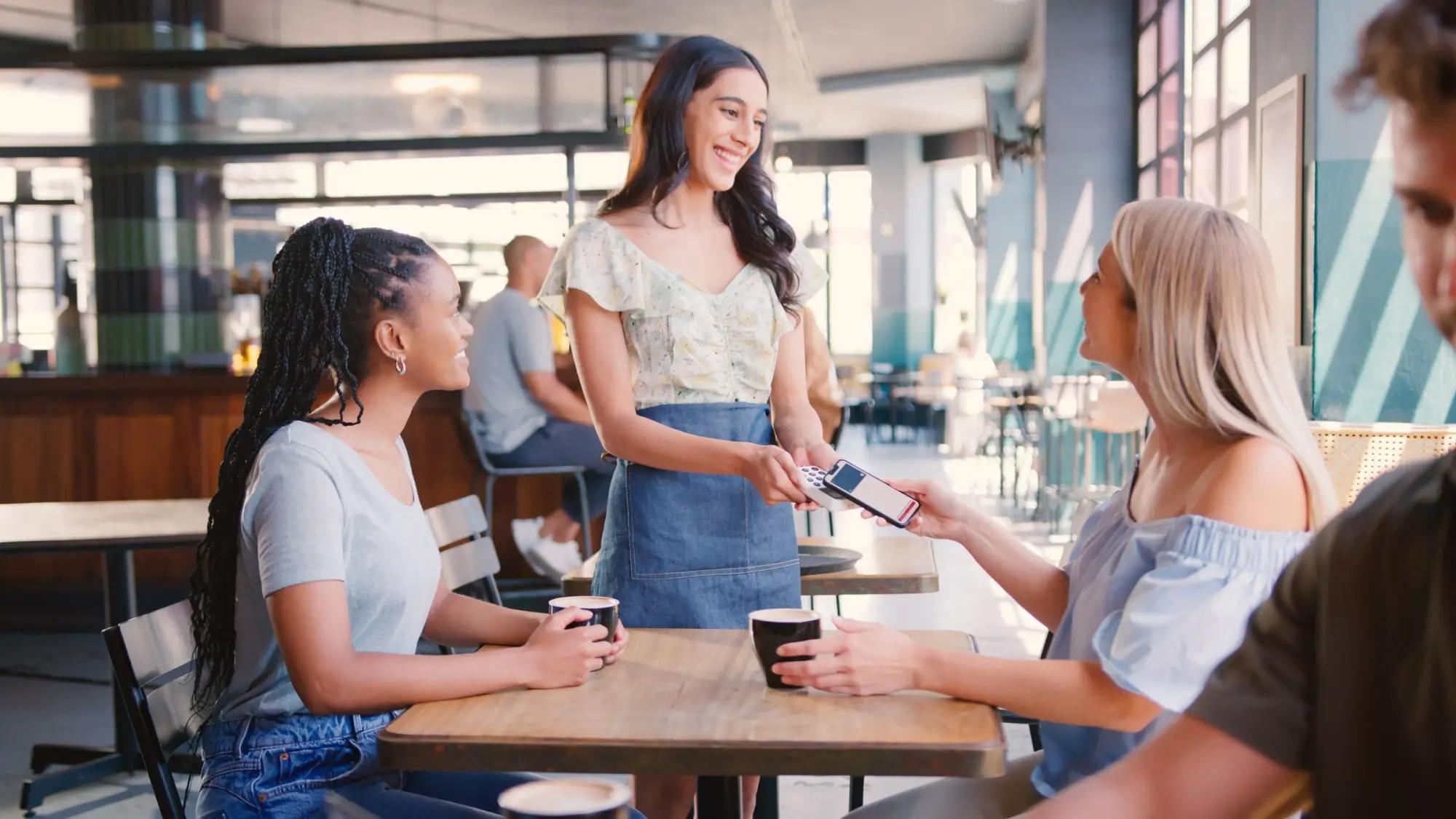 Ženy v kavárně platí mobilem