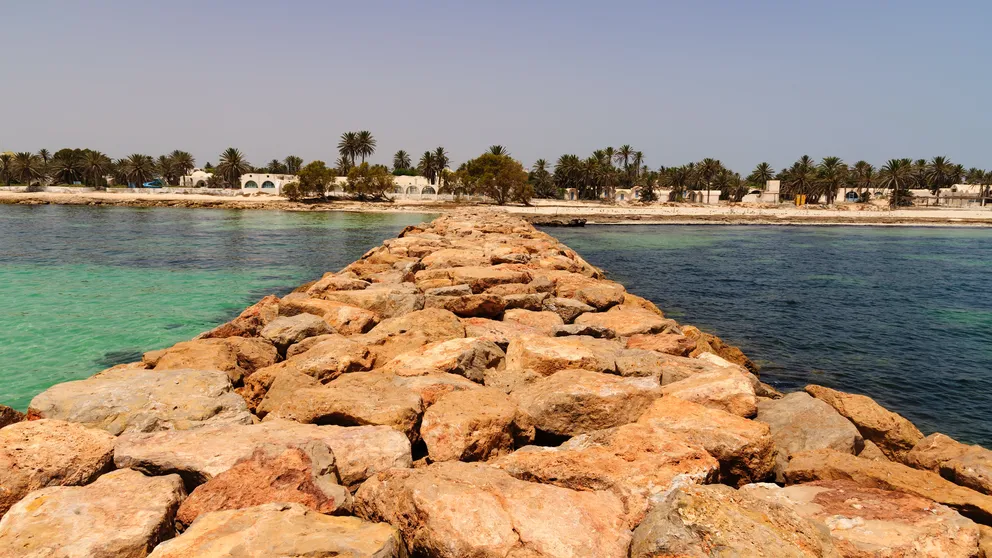 Kamenné molo vedoucí od osídlené pláže do moře, Djerba/Tunisko.