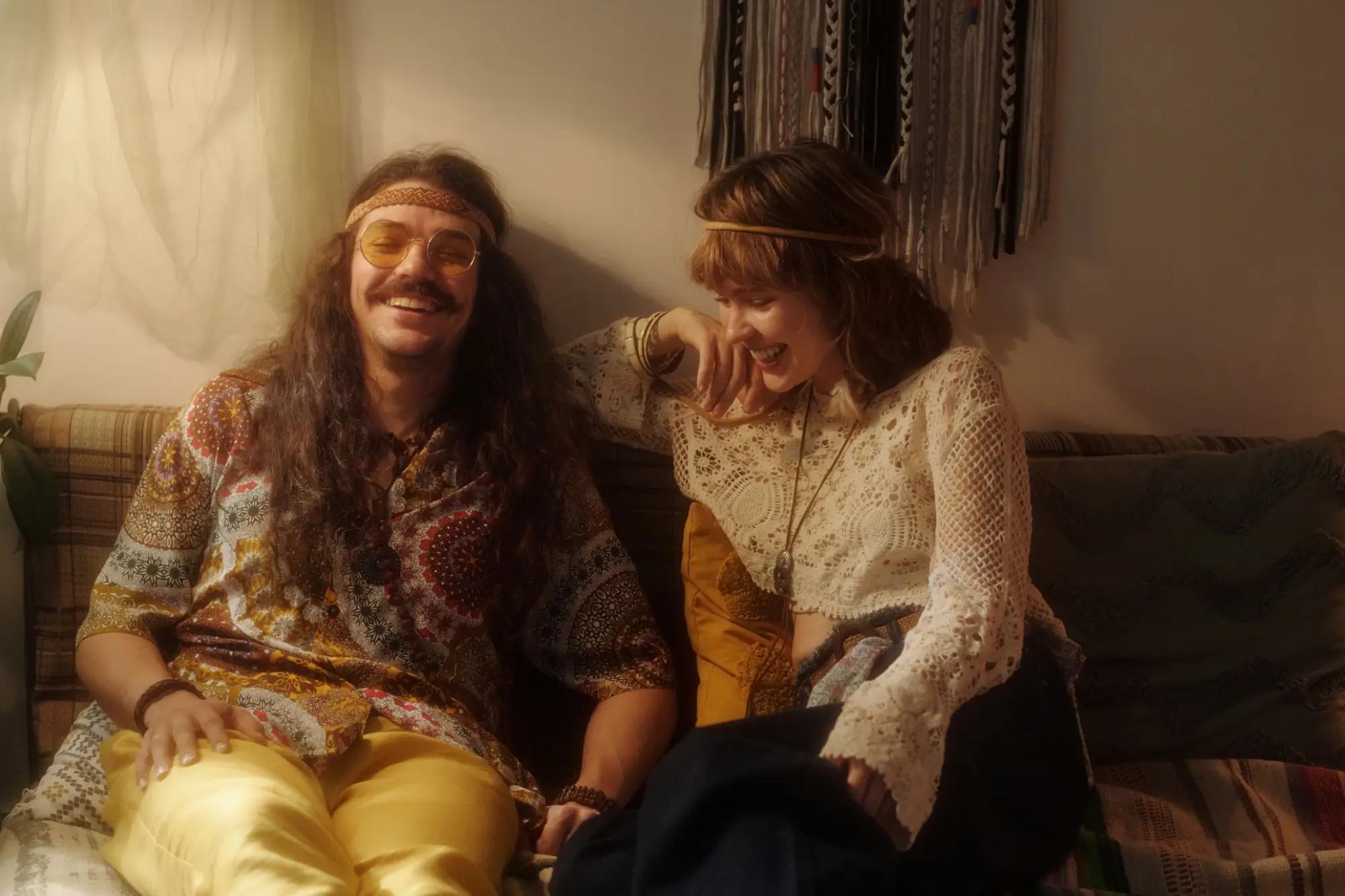 Pár hippies sedí na sedačce a směje se