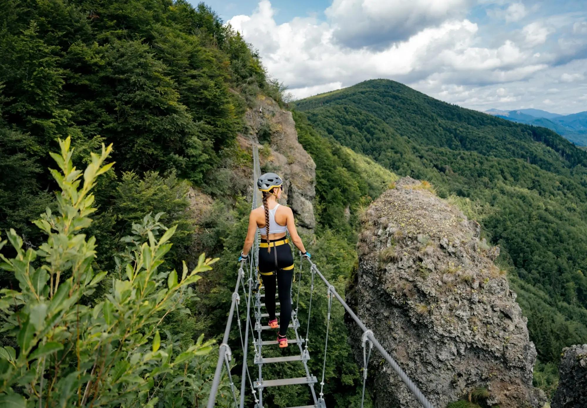 žena na žebříkovém mostě si užívá výhled na krajinu