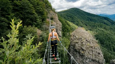 žena na žebříkovém mostě si užívá výhled na krajinu