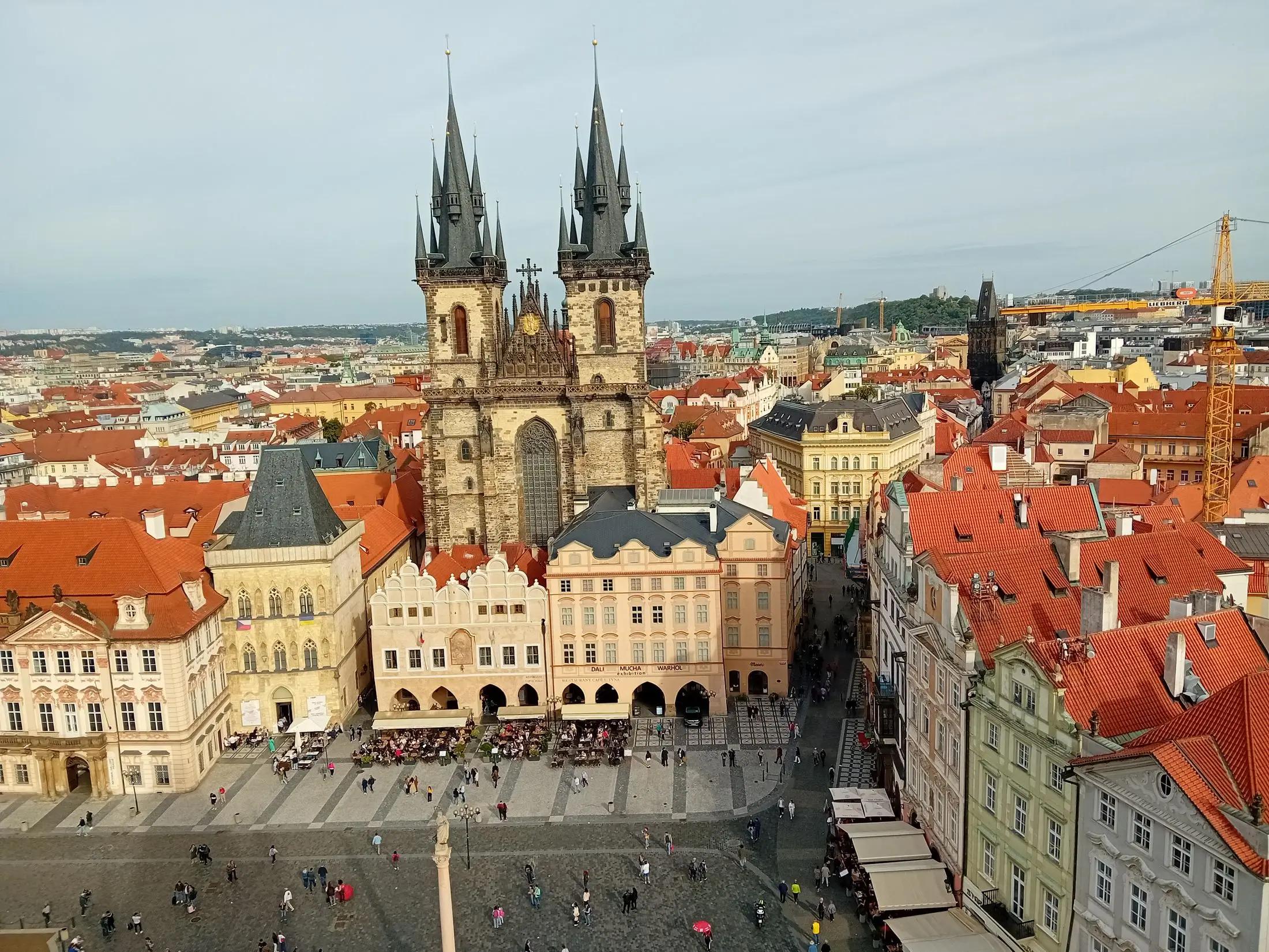 Panoramatický pohled na Týnský chrám a jeho okolní budovy. Je krásný den, obloha je modrá.