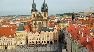 Panoramatický pohled na Týnský chrám a jeho okolní budovy. Je krásný den, obloha je modrá.