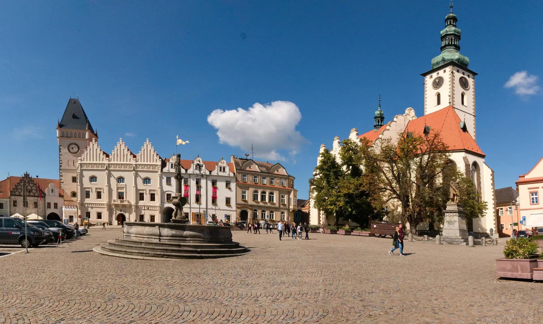 Žižkovo náměstí ve městě Tábor. Je krásný, nejspíše letní den. Je tu hrstka lidí.