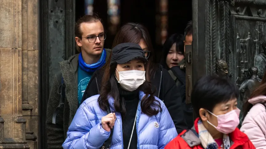 asijští turisté s rouškami opouštějí katedrálu v Praze