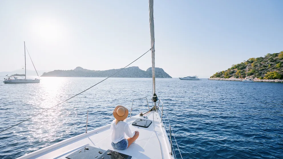 Luxusní cestování na jachtě. Mladá šťastná žena na palubě lodi plující po moři. Jachting v Řecku