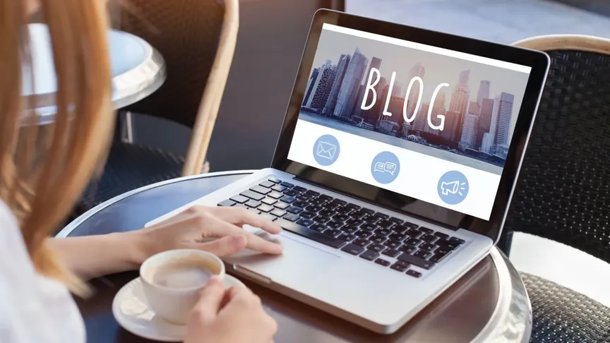 Žen má před sebou na stolku kafe a otevřený notebook. Jde číst/psát blog.