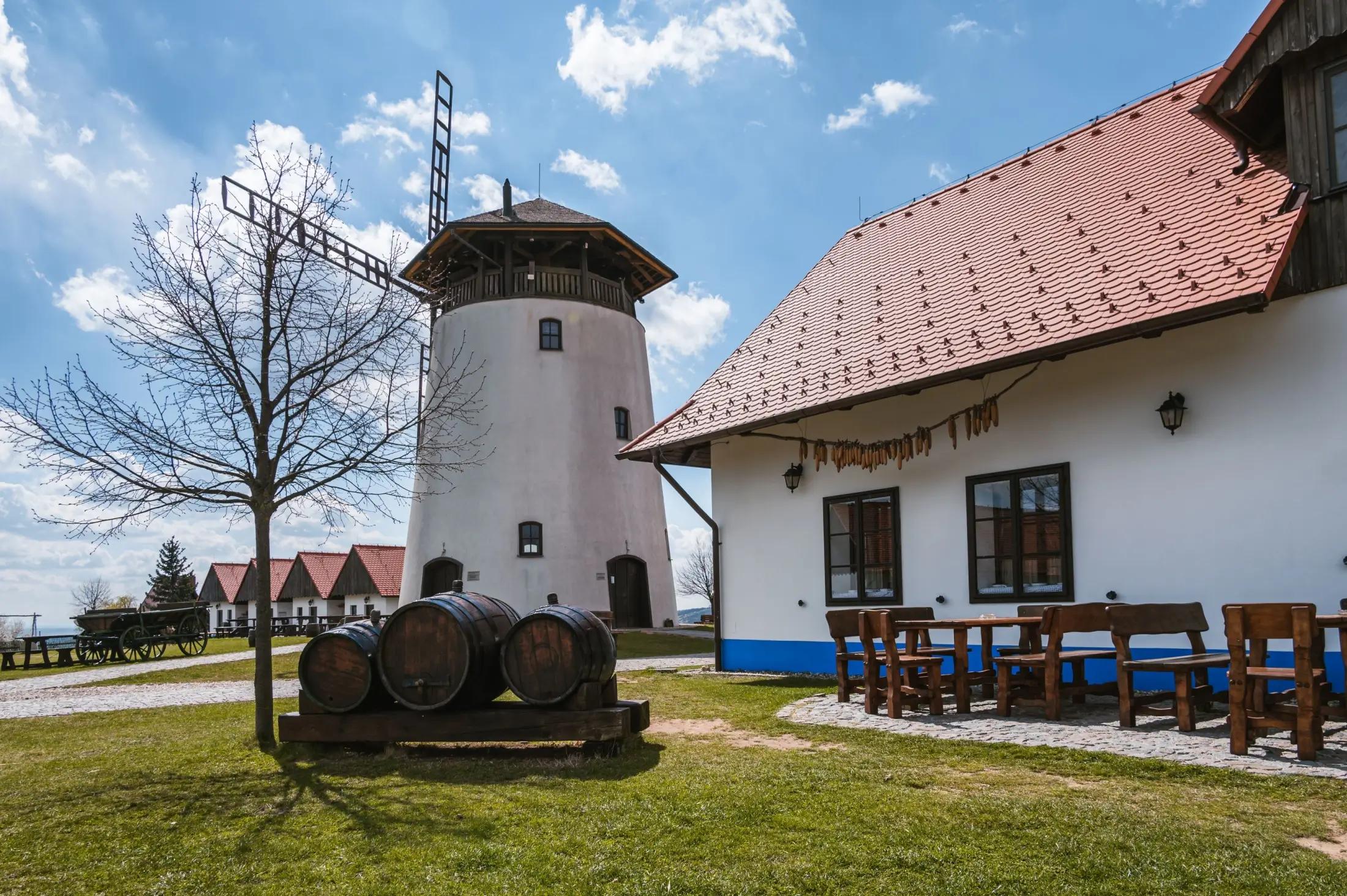 Bukovanský mlýn s tradičním domem na pravé straně obrázku. Nejspíše je podzim, na levé straně je vidět strom s opadaným listím.
