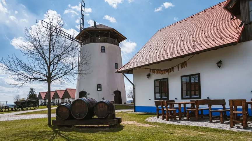 Bukovanský mlýn s tradičním domem na pravé straně obrázku. Nejspíše je podzim, na levé straně je vidět strom s opadaným listím.