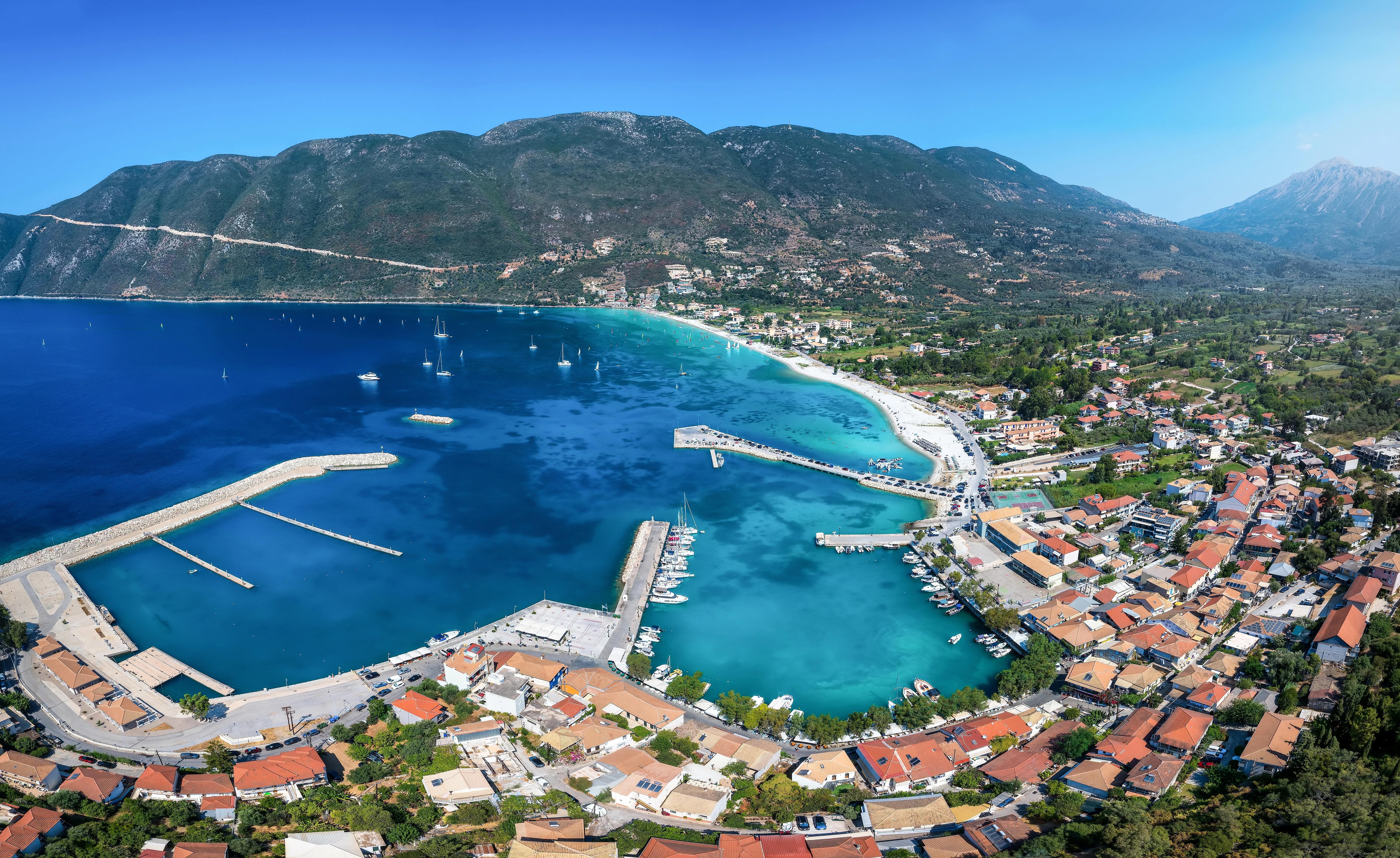 Letecký pohled na malou vesnici obklopující azurovo-modrý přístav Vassiliki na ostrově Lefkada, Jónské moře, Řecko