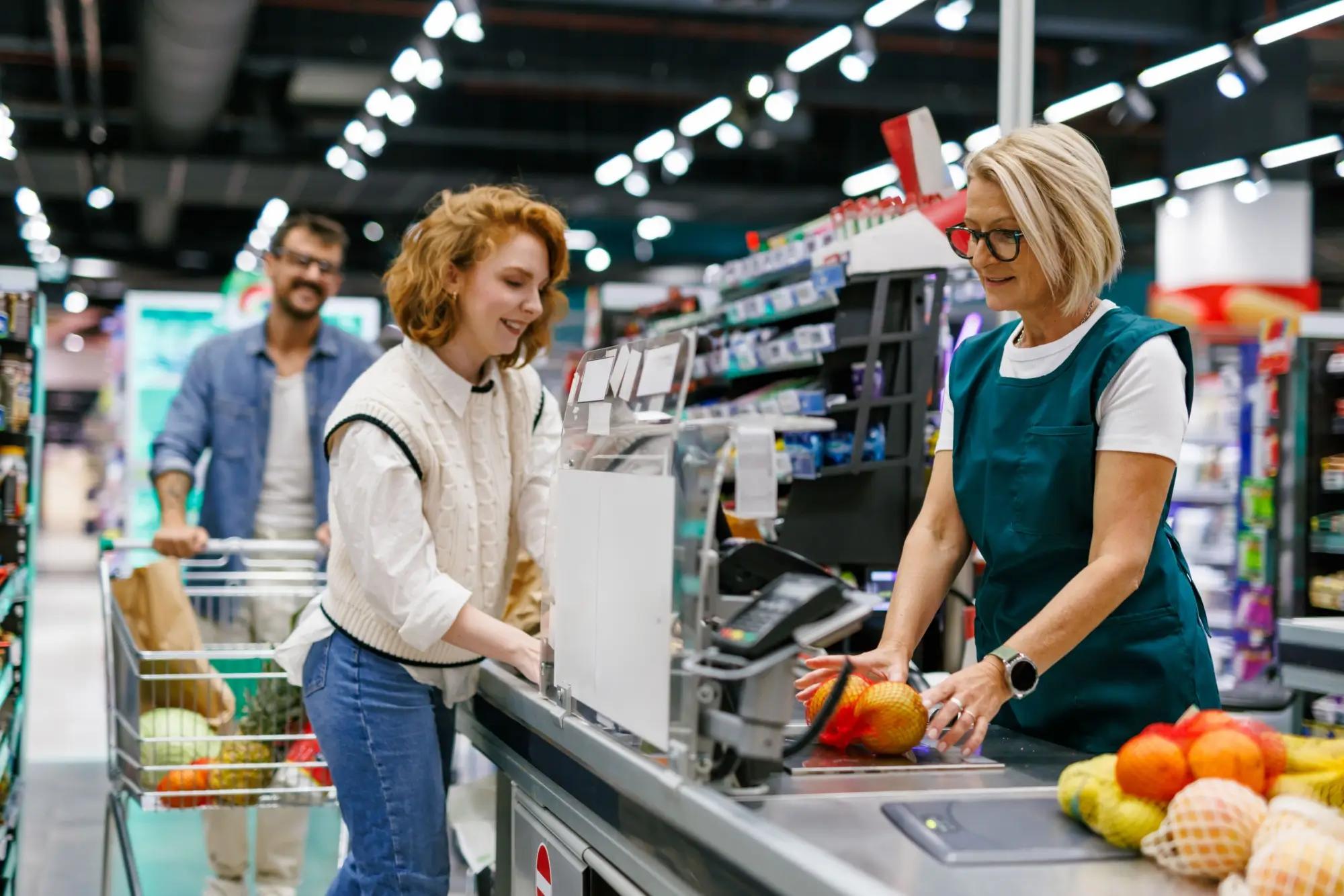 Prodavačka při obsluze zákaznice na pokladně 
